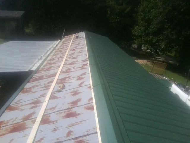 Old rusted panels beside newly installed green metal roofing — Wind Damage Roof Repair by Roofing Brothers in Valley Cottage