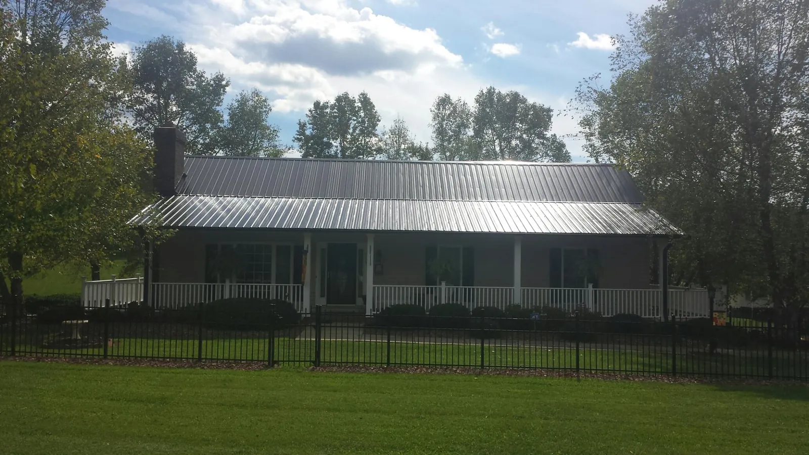 Gray metal roof on a brick ranch with a full width front porch — Gutter Guard Installation work by our crew in Valley Cottage