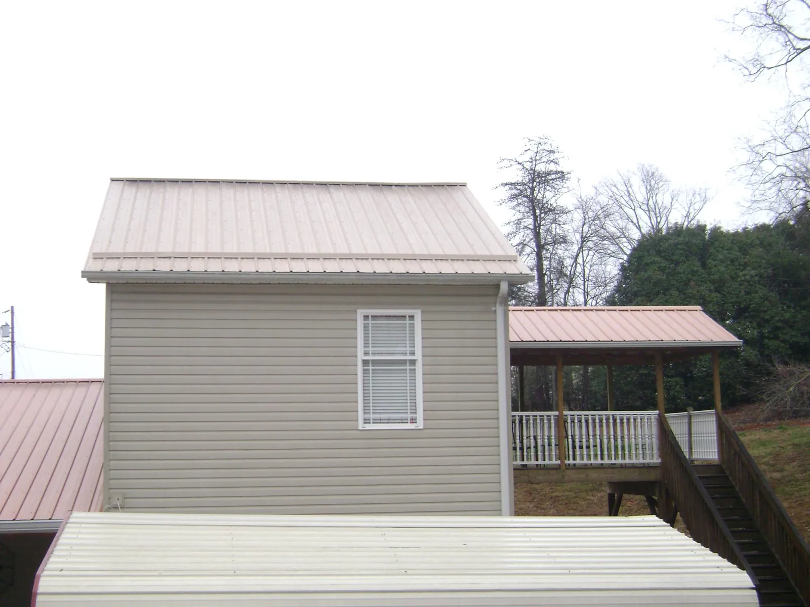 Tan metal roofs on a two story addition and attached porch, from a Roof Replacement job in Valley Cottage