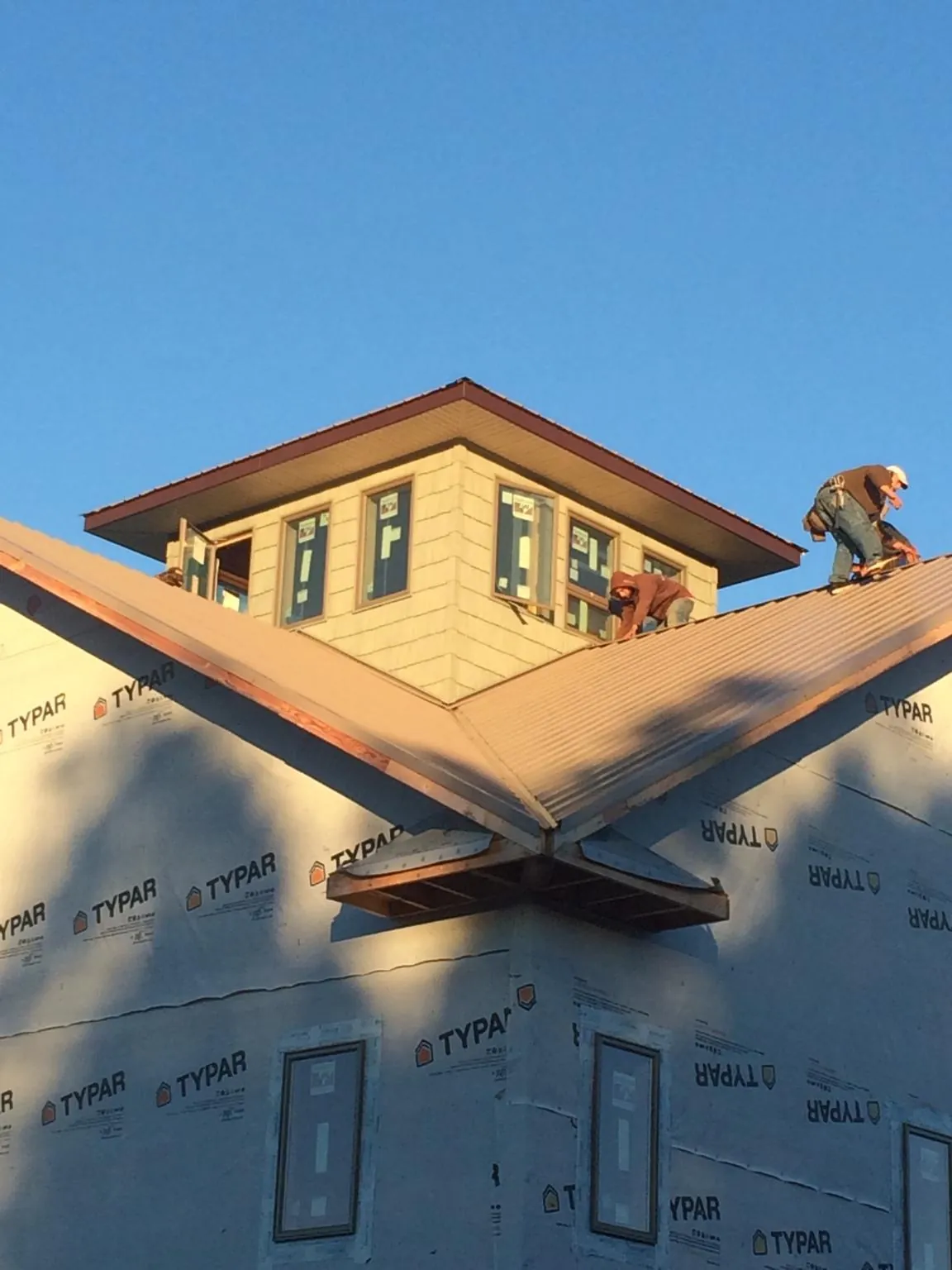 Roofers working around a rooftop cupola on a new metal roof at sunset — Roof Waterproofing in Valley Cottage by Roofing Brothers